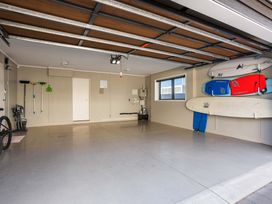 A garage with a bicycle and surfboards mounted on the wall at Sunbrae Sands - Mount Maunganui Holiday Homes