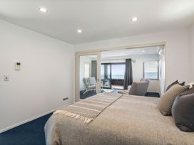 A bedroom with a bed and sliding doors at Sunbrae Sands - Mount Maunganui Holiday Homes Mount Maunganui