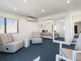 A bedroom with reclining chairs and a mirror at Sunbrae Sands - Mount Maunganui