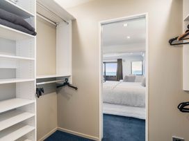 A closet with shelves and hangers leading to a bedroom at Sunbrae Sands - Mount Maunganui Holiday Homes