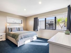 A bedroom with a bed and windows at Sunbrae Sands - Mount Maunganui Holiday Homes