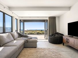 A living room with a sofa and a television at Sunbrae Sands - Mount Maunganui
