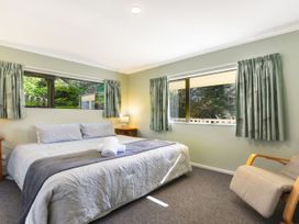 A bedroom with a bed and windows at Tepuia Cottage - Havelock Holiday Retreat Marlborough