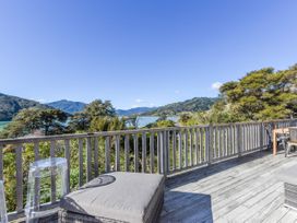 A deck with outdoor furniture and a view of water and mountains at Tepuia Cottage - Havelock Holiday Retreat Marlborough