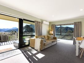 A living room with a sofa, lamp, and dining table at Tepuia Cottage - Havelock Holiday Retreat Marlborough