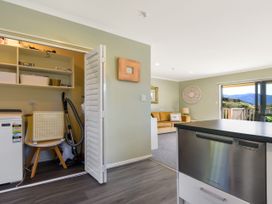 A kitchen with a washing machine and shelves at Tepuia Cottage - Havelock Holiday Retreat Marlborough