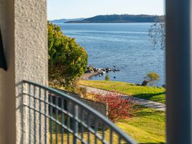A view of a lake with grass and a path at Rainbow Point Yacht Club - Taupo Holiday Home, Taupo