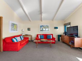 A living room with red sofas and a television at Rainbow Point Yacht Club - Taupo