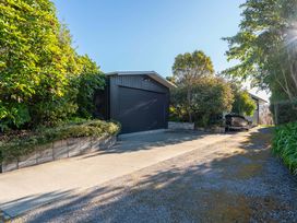 A garage with a gravel driveway and vegetation at Rainbow Point Yacht Club - Taupo Holiday Home Taupo