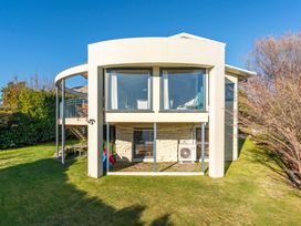 An exterior view of a house with large windows and a garden at Rainbow Point Yacht Club - Taupo