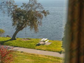 An outdoor area with a picnic table and tree next to water at Rainbow Point Yacht Club - Taupo