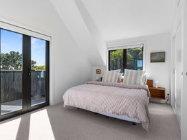 A bedroom with a bed and windows at Langs Beach Holiday Home in Langs Beach