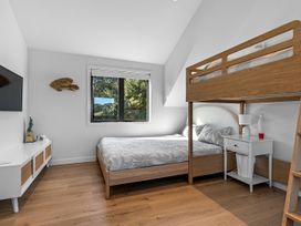 A bedroom with a bunk bed and a television at Langs Beach Holiday Home, Langs Beach