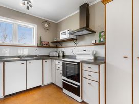 A kitchen with an oven, sink, and cabinets at Rockstar Retreat - Auckland Holiday Home, Red Beach