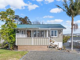 A house with a balcony and garden at Rockstar Retreat - Auckland Holiday Home Red Beach