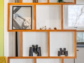 A shelf displaying a photo frame and binoculars at Rockstar Retreat - Auckland Holiday Home Red Beach