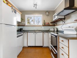 A kitchen with a refrigerator, microwave, and sink at Rockstar Retreat - Auckland Holiday Home, Red Beach