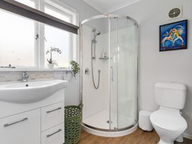 A bathroom with a shower, sink, and toilet at Rockstar Retreat - Auckland Holiday Home, Red Beach