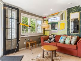 A living room with a telescope and a sofa at Rockstar Retreat - Auckland Holiday Home, Red Beach