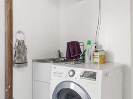 A laundry room with a washing machine and sink at Rockstar Retreat - Auckland Holiday Home Red Beach