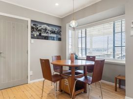 A dining room with a round table and chairs at Rockstar Retreat - Auckland Holiday Home, Red Beach