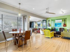 A living room with a table and chairs near a sofa at Rockstar Retreat - Auckland Holiday Home Red Beach