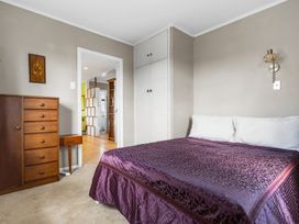 A bedroom with a bed and chest of drawers at Rockstar Retreat - Auckland Holiday Home, Red Beach