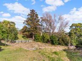 A garden area with trees and a fence at Rockstar Retreat - Auckland Holiday Home Red Beach