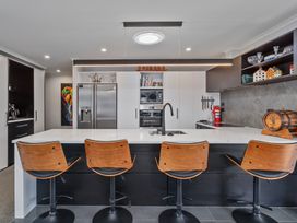 A kitchen with a countertop, stools, and appliances at Endeavour Oasis - Whitianga