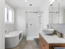 A bathroom with a bathtub, shower, toilet, and sink at Auckland Holiday Home in Auckland