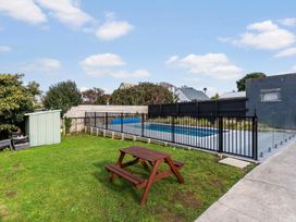 A garden with a pool, table, and shed at Auckland Holiday Home in Auckland