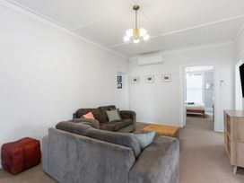 A living room with a sofa and an ottoman at Auckland Holiday Home in Auckland