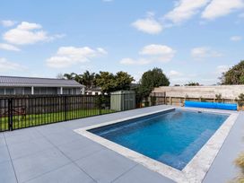 A swimming pool with a deck and shed in the garden at Auckland Holiday Home in Auckland