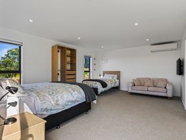 A bedroom with two beds and a sofa at Mangawhai Holiday Home in Mangawhai