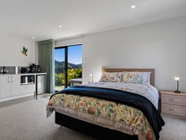 A bedroom with a bed and kitchenette at Mangawhai Holiday Home in Mangawhai