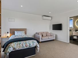 A bedroom with a bed and a couch at Mangawhai Holiday Home Mangawhai