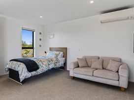 A bedroom with a bed and sofa at Mangawhai Holiday Home in Mangawhai