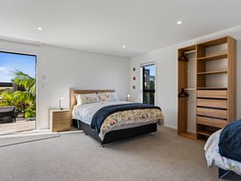 A bedroom with a bed and a wardrobe at Mangawhai Holiday Home Mangawhai