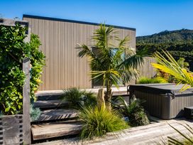 An outdoor area with a palm tree and a spa at Mangawhai Holiday Home in Mangawhai