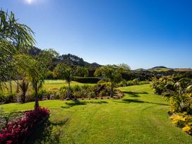 A garden with palm trees and flowers at Mangawhai Holiday Home in Mangawhai