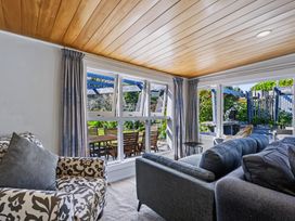A living room with a sofa and chair by the window at Hannan House - Whitianga Holiday Home
