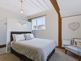 A bedroom with a bed and chair at Hannan House - Whitianga Holiday Home