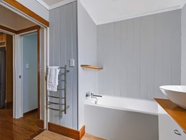 A bathroom featuring a bath tub and wash basin at Hannan House - Whitianga Holiday Home