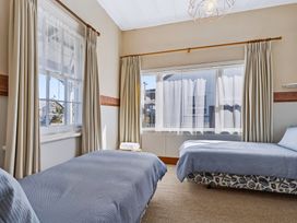 A bedroom with two beds and windows at Hannan House - Whitianga Holiday Home