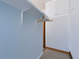A hallway with a hanger on a shelf and a door at Hannan House - Whitianga Holiday Home