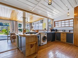 A kitchen with a stove and washing machine at Hannan House - Whitianga Holiday Home