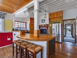 A kitchen with a cooking area and seating at Hannan House - Whitianga Holiday Home