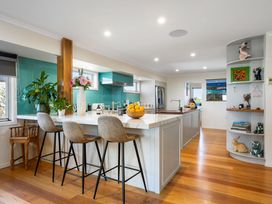 A kitchen with bar stools and a sink at Ohana - Papamoa Holiday Home, Papamoa