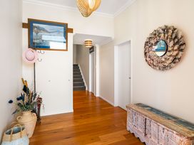 A hallway with a painting, hat rack, vase, and mirror at Ohana - Papamoa Holiday Home, Papamoa