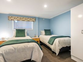 A bedroom with two single beds and a window at Ohana - Papamoa Holiday Home Papamoa